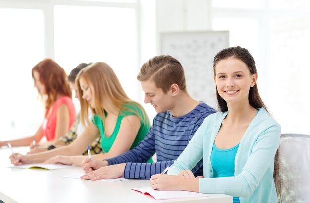 concetto di istruzione e scuola - cinque studenti sorridenti con libri di testo a scuola