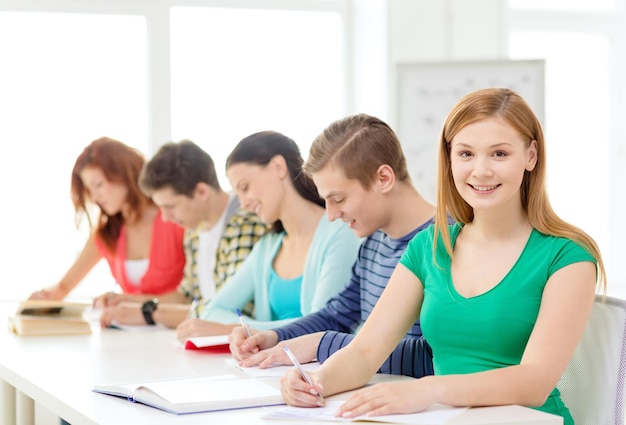 concetto di istruzione e scuola - cinque studenti sorridenti con libri di testo e libri a scuola