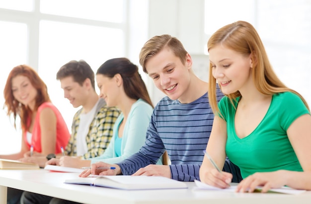 concetto di istruzione e scuola - cinque studenti sorridenti con libri di testo e libri a scuola