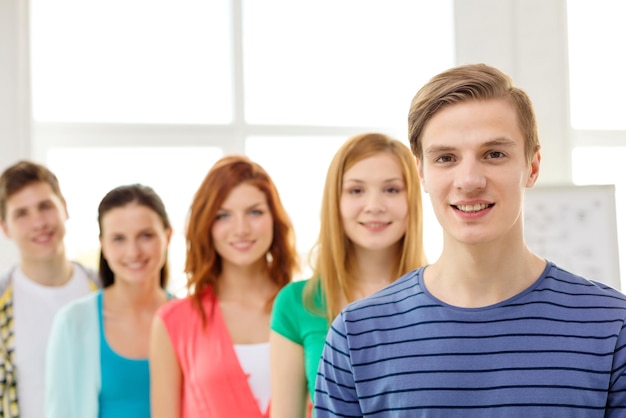 concetto di istruzione e scuola - gruppo di studenti sorridenti con un adolescente di fronte