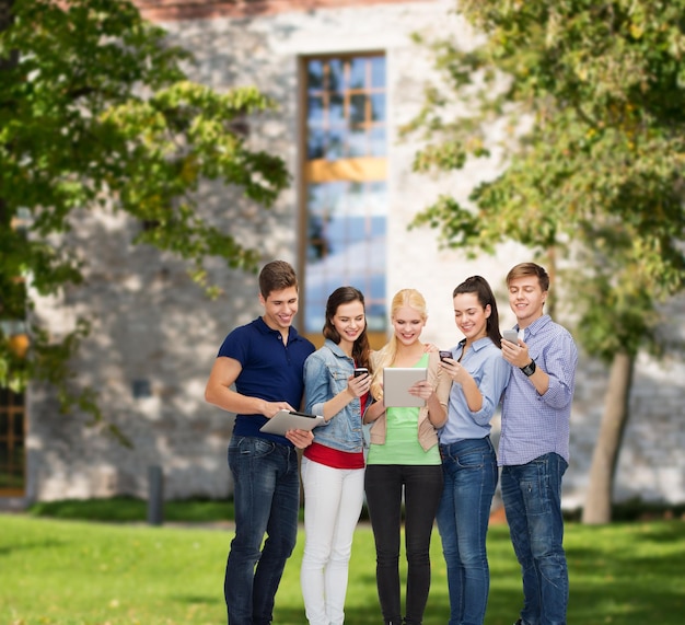 concetto di istruzione e tecnologia moderna - studenti sorridenti che utilizzano smartphone e tablet pc