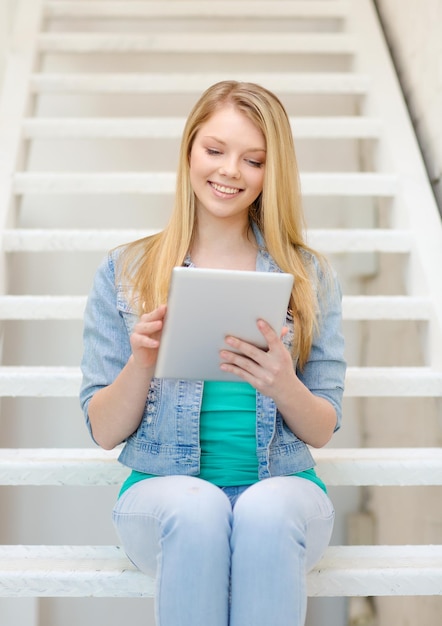 concetto di istruzione e tecnologia - studentessa sorridente con computer tablet pc seduto sulla scala