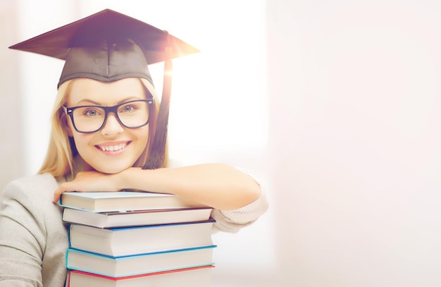 concetto di istruzione - immagine di studente felice in protezione di laurea con pila di libri