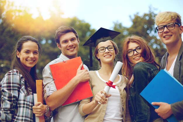 concetto di istruzione, laurea e persone - gruppo di studenti sorridenti in sparviere con cartelle di diploma e scuola