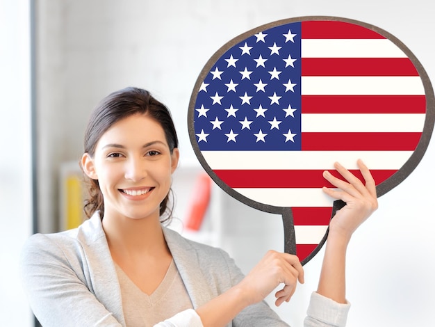 concetto di istruzione, lingua straniera, inglese, persone e comunicazione - donna sorridente che tiene bolla di testo della bandiera americana