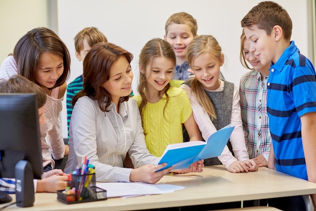 concetto di istruzione, scuola elementare, apprendimento e persone - gruppo di bambini delle scuole con insegnante che parla in classe