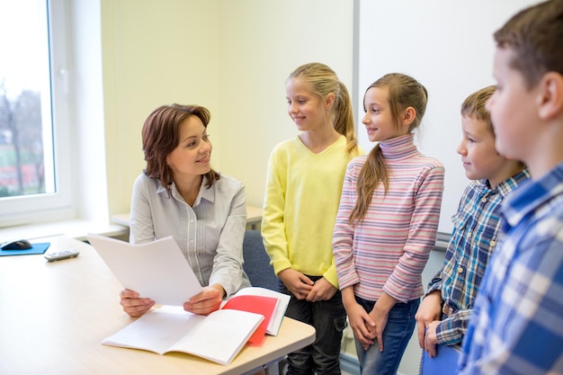 concetto di istruzione, scuola elementare, apprendimento e persone - gruppo di bambini delle scuole con insegnante che parla in classe