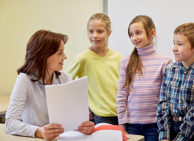 concetto di istruzione, scuola elementare, apprendimento e persone - gruppo di bambini delle scuole con insegnante che parla in classe