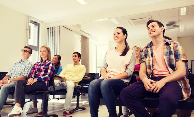 concetto di istruzione, scuola superiore, lavoro di squadra e persone - gruppo di studenti sorridenti seduti in aula