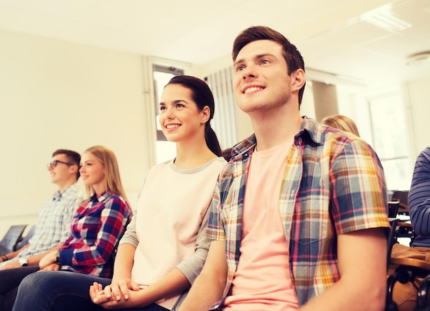 concetto di istruzione, scuola superiore, lavoro di squadra e persone - gruppo di studenti sorridenti seduti in aula