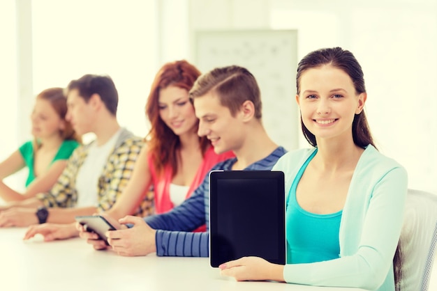 concetto di istruzione, tecnologia e internet - adolescente sorridente davanti agli studenti che mostrano lo schermo vuoto del computer tablet pc a scuola