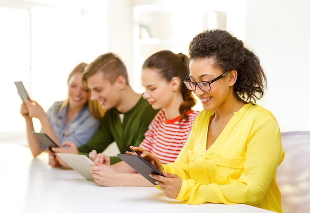 concetto di istruzione, tecnologia e internet - studenti sorridenti che guardano il computer tablet pc a scuola