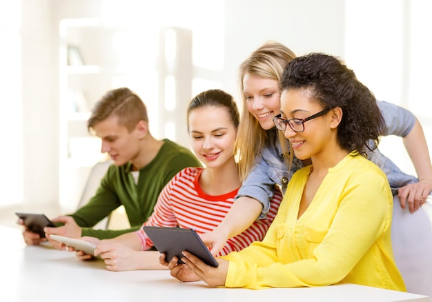 concetto di istruzione, tecnologia e internet - studenti sorridenti che guardano il computer tablet pc a scuola