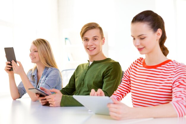 concetto di istruzione, tecnologia e internet - studenti sorridenti che guardano il computer tablet pc a scuola