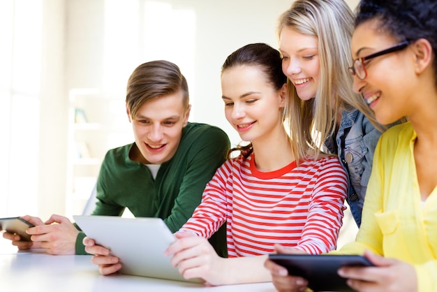 concetto di istruzione, tecnologia e internet - studenti sorridenti che guardano il computer tablet pc a scuola