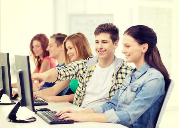 concetto di istruzione, tecnologia e scuola - studentessa sorridente con compagni di classe in classe di computer a scuola
