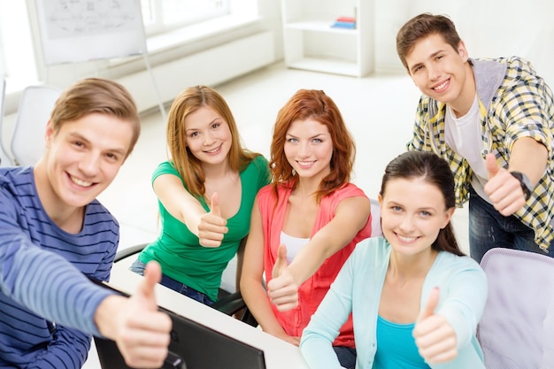 concetto di istruzione, tecnologia, scuola e persone - gruppo di studenti sorridenti che mostrano i pollici in su in classe di computer a scuola