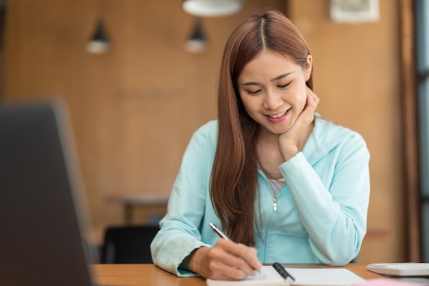 Concetto di istruzione universitaria Ragazza adolescente che guarda il video tutorial del tutor sul laptop e prende appunti