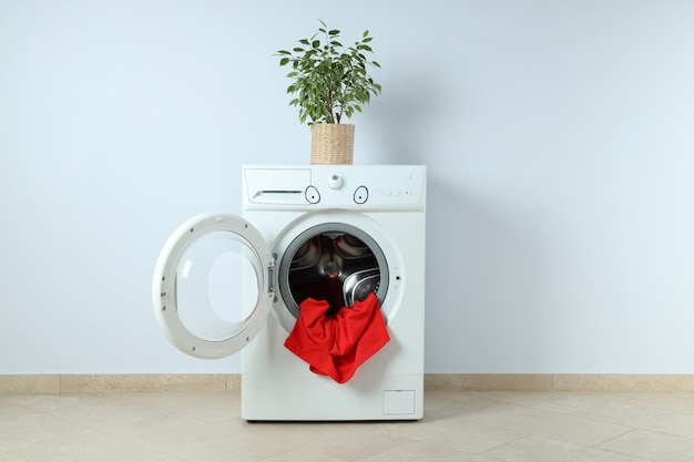 Concetto di lavori domestici con lavatrice contro il muro bianco