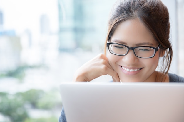 Concetto di lavoro a casa con giovane adulto asiatico che sorride con il computer portatile