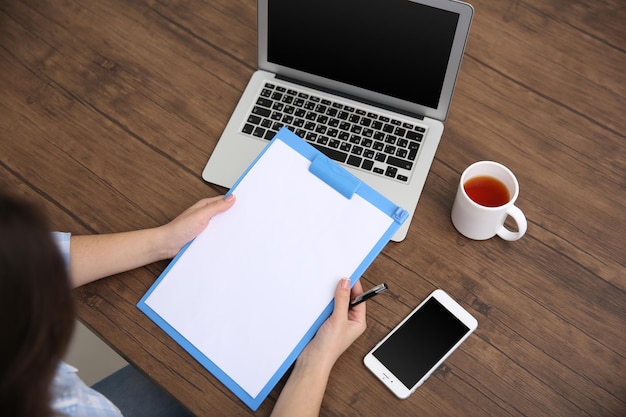 Concetto di lavoro Appunti nelle mani della donna Computer portatile e tazza di tè sul tavolo di legno