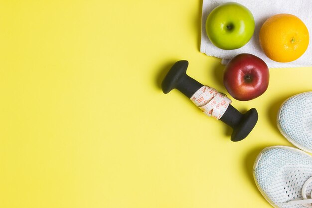 Concetto di lavoro con scarpe da ginnastica a orologio arancione e manubrio sullo sfondo giallo