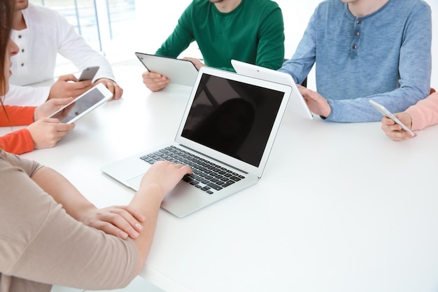 Concetto di lavoro di squadra Persone sedute al tavolo in ufficio e che utilizzano dispositivi digitali