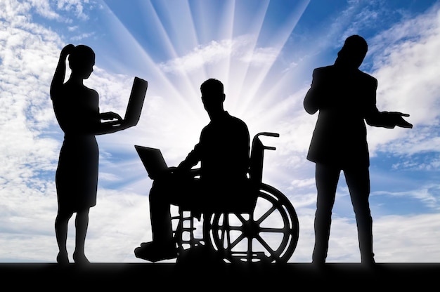 Concetto di lavoro disabile Silhouette di un uomo lavoratore disabile su sedia a rotelle con un laptop e il suo