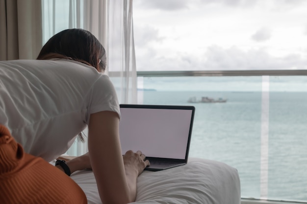 Concetto di lavoro donna lavora su laptop in una camera d'albergo con vista mare
