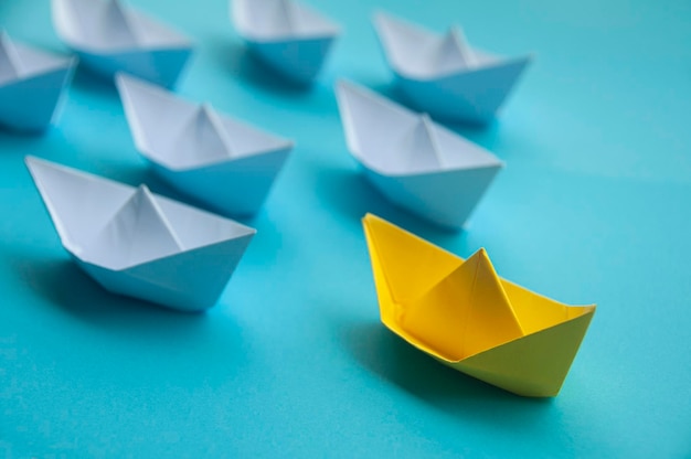 Concetto di leadership Origami di nave di carta di colore giallo che guida il resto della nave di carta bianca su sfondo blu della copertina Concetto di spazio di copia