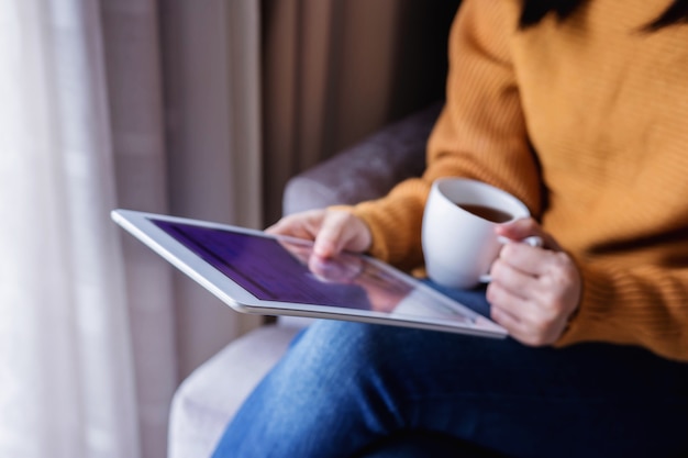 Concetto di lettura. Giovane donna che usando Tablet e bere caffè.