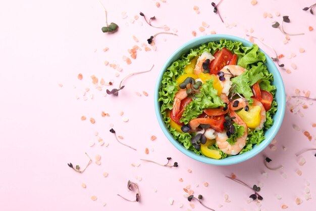 Concetto di mangiare gustoso con insalata di gamberi su sfondo rosa