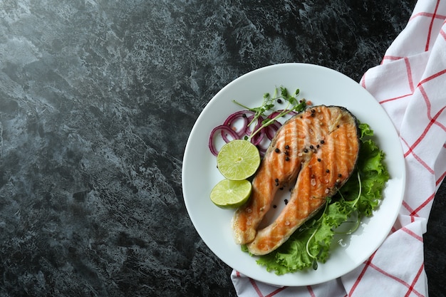 Concetto di mangiare gustoso con salmone alla griglia su sfondo nero affumicato