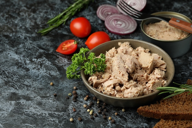 Concetto di mangiare gustoso con tonno in scatola su sfondo nero affumicato