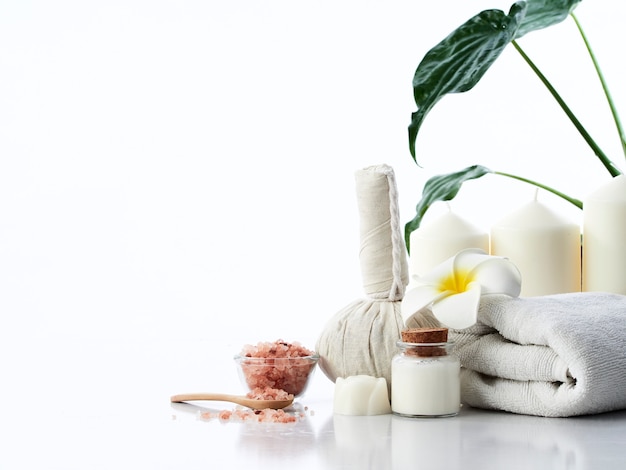 Concetto di massaggio spa, palla impacco alle erbe, crema, sapone ai fiori, candela profumata e sale rosa dell'Himalaya, isolato