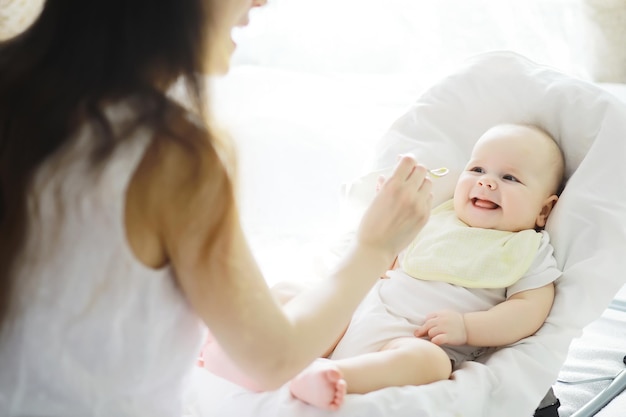 Concetto di maternità Una giovane madre nutre il suo bambino Prima esca e allattamento Grande famiglia in abiti bianchi