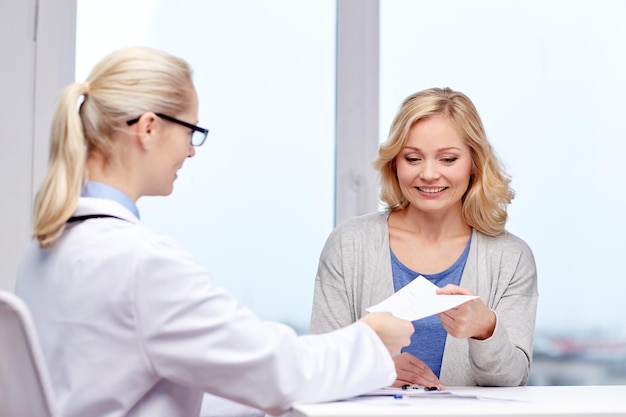 concetto di medicina, assistenza sanitaria, incontro e persone - medico sorridente che fornisce prescrizione medica o certificato a una donna in ospedale