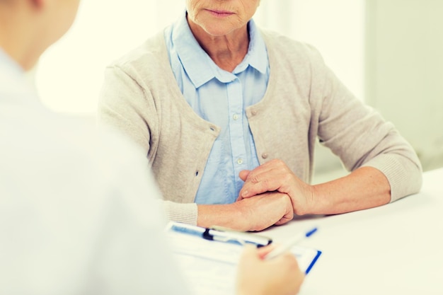 concetto di medicina, età, assistenza sanitaria e persone - primo piano delle mani del medico e della donna senior con la riunione degli appunti in studio medico