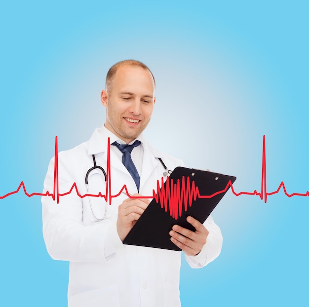 concetto di medicina, professione, cardiologia e assistenza sanitaria - medico maschio sorridente con appunti e stetoscopio che scrive prescrizione su sfondo cardiogramma