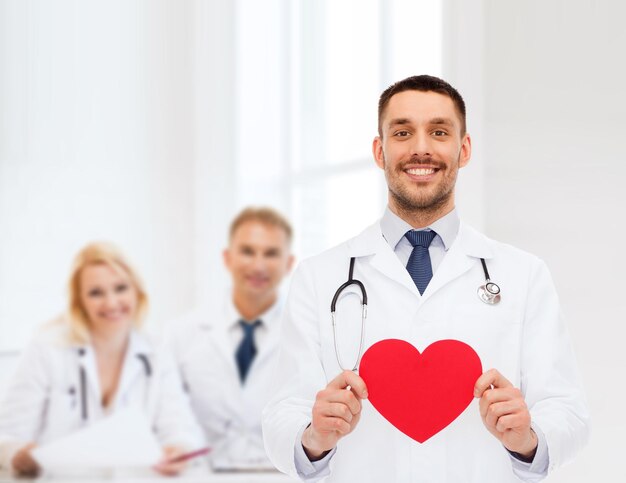 concetto di medicina, professione e assistenza sanitaria - medico maschio sorridente con cuore rosso e stetoscopio