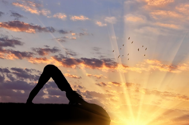 Concetto di meditazione e rilassamento. Siluetta di una ragazza che pratica esercizio di yoga sullo sfondo del tramonto