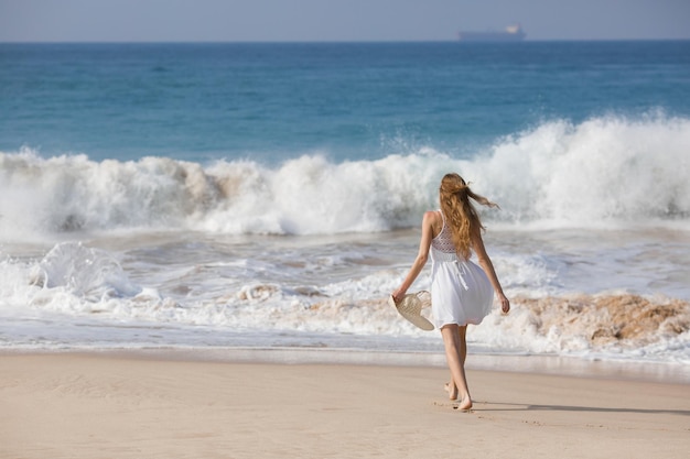 Concetto di moda per le vacanze estive donna abbronzante che indossa il cappello da sole in spiaggia su una sabbia bianca ripresa dall'alto