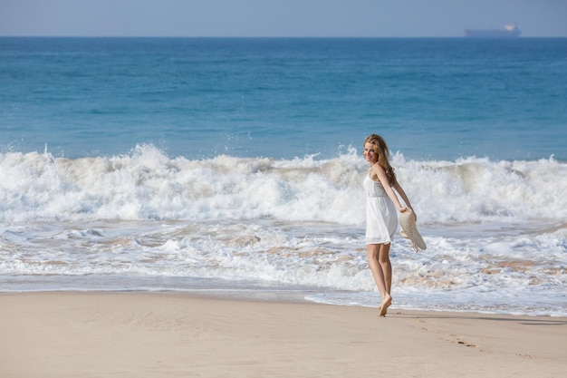 Concetto di moda per le vacanze estive donna abbronzante che indossa il cappello da sole in spiaggia su una sabbia bianca ripresa dall'alto