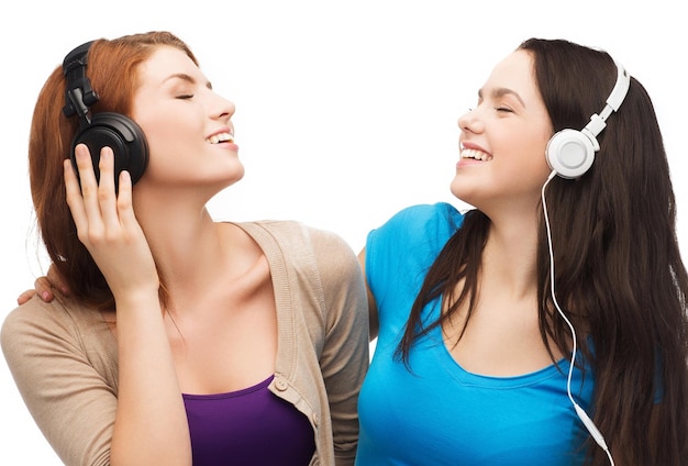 concetto di musica e tecnologia - due adolescenti sorridenti con gli occhi chiusi che ascoltano musica con le cuffie