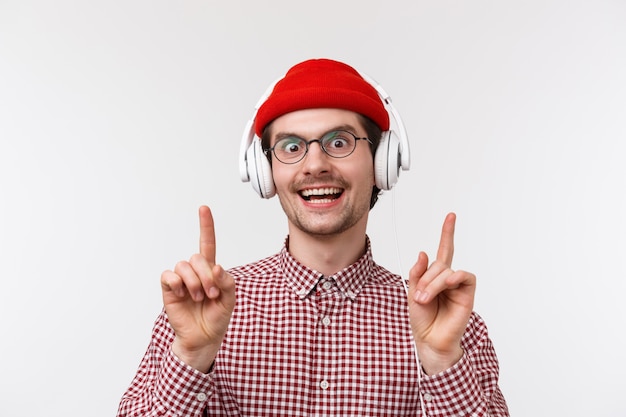 Concetto di musica, tecnologia e persone. Groovie carino uomo barbuto con gli occhiali e berretto rosso