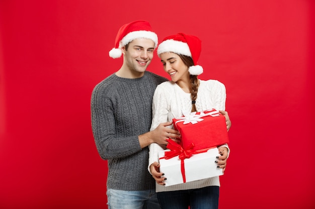 Concetto di Natale - bel giovane ragazzo in maglione di Natale sorprende la sua ragazza con i regali.