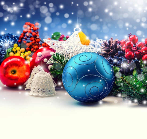 Concetto di Natale composto da palla blu, mele adorabili, piccoli rami d'albero, stelle e sfondo bokeh.