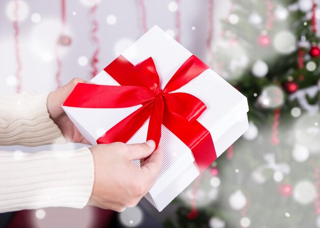 Concetto di Natale - confezione regalo in mani maschili su interni natalizi decorati