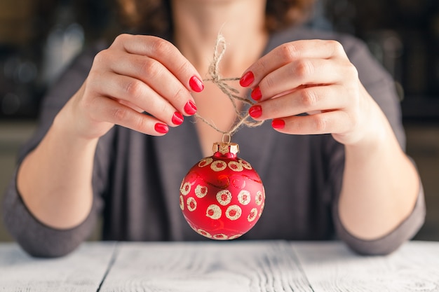 Concetto di Natale, della decorazione, di feste e della gente - vicino su della palla di rosso di natale della tenuta della mano della donna