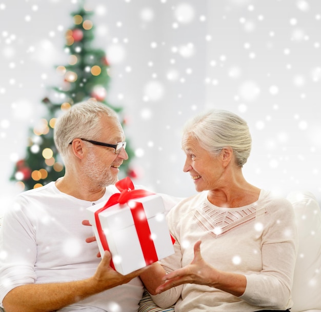 concetto di natale, famiglia, vacanze, età e persone - coppia senior felice con confezione regalo e neve